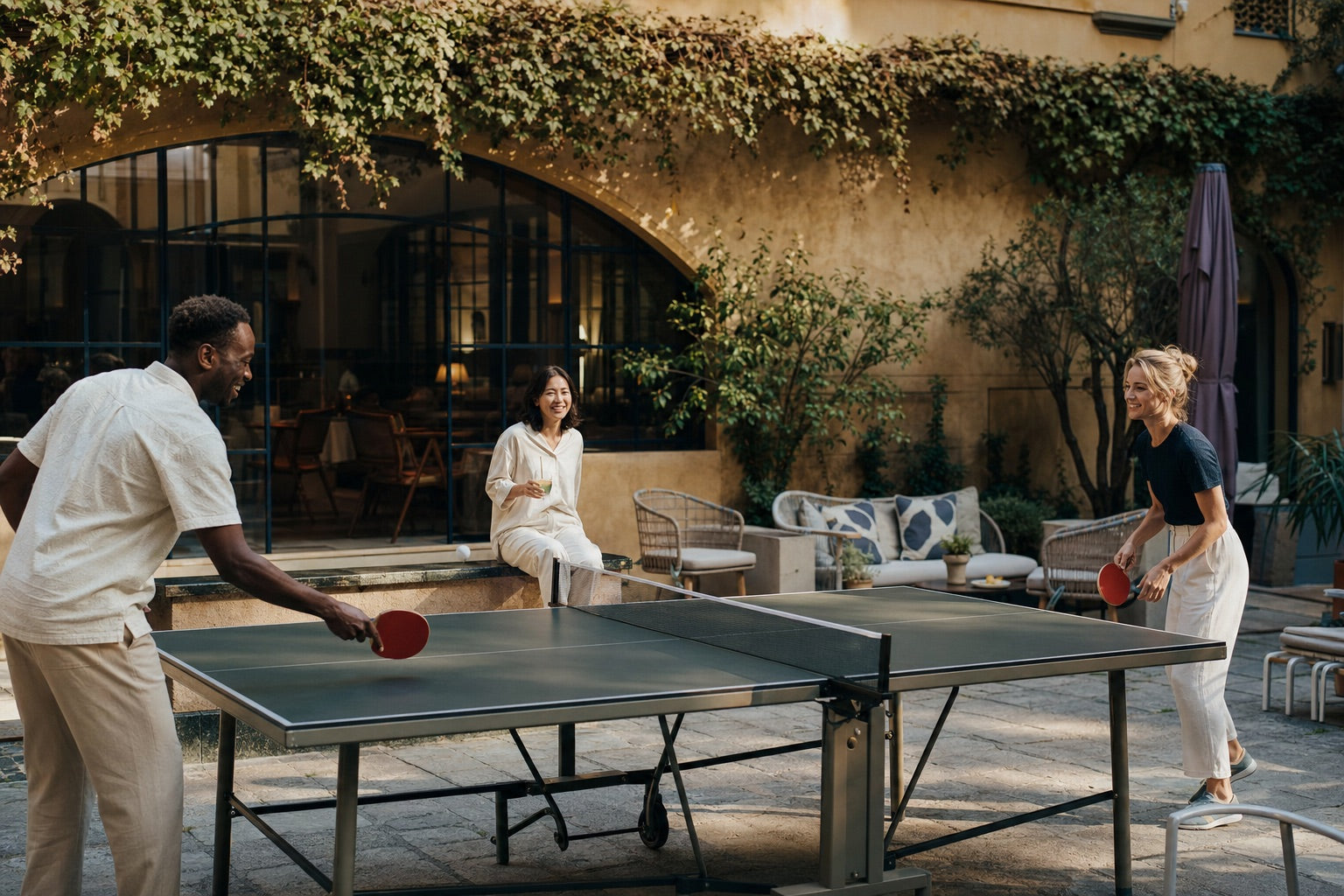 Gäste spielen im Innenhof eines Hotels gemeinsam Tischtennis