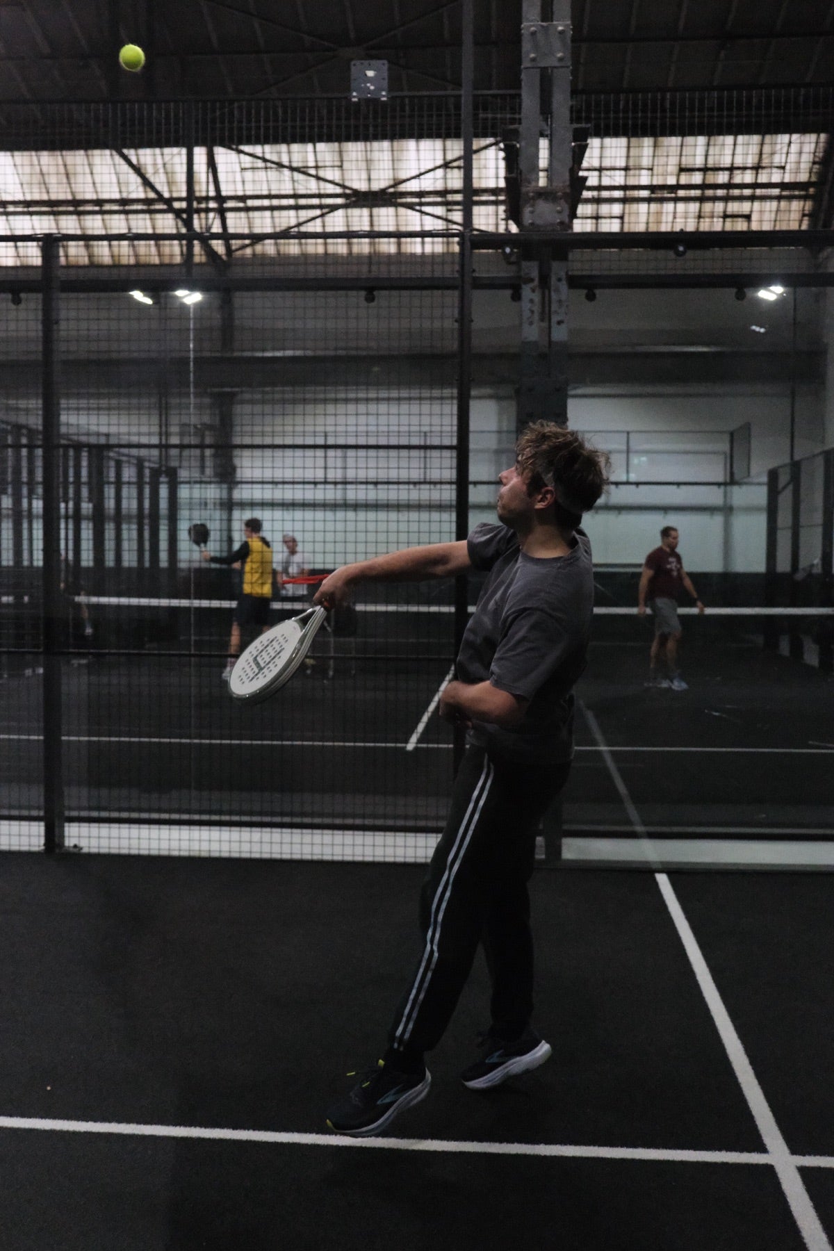padel spieler mit heinsa schläger beim aufschlag in der halle