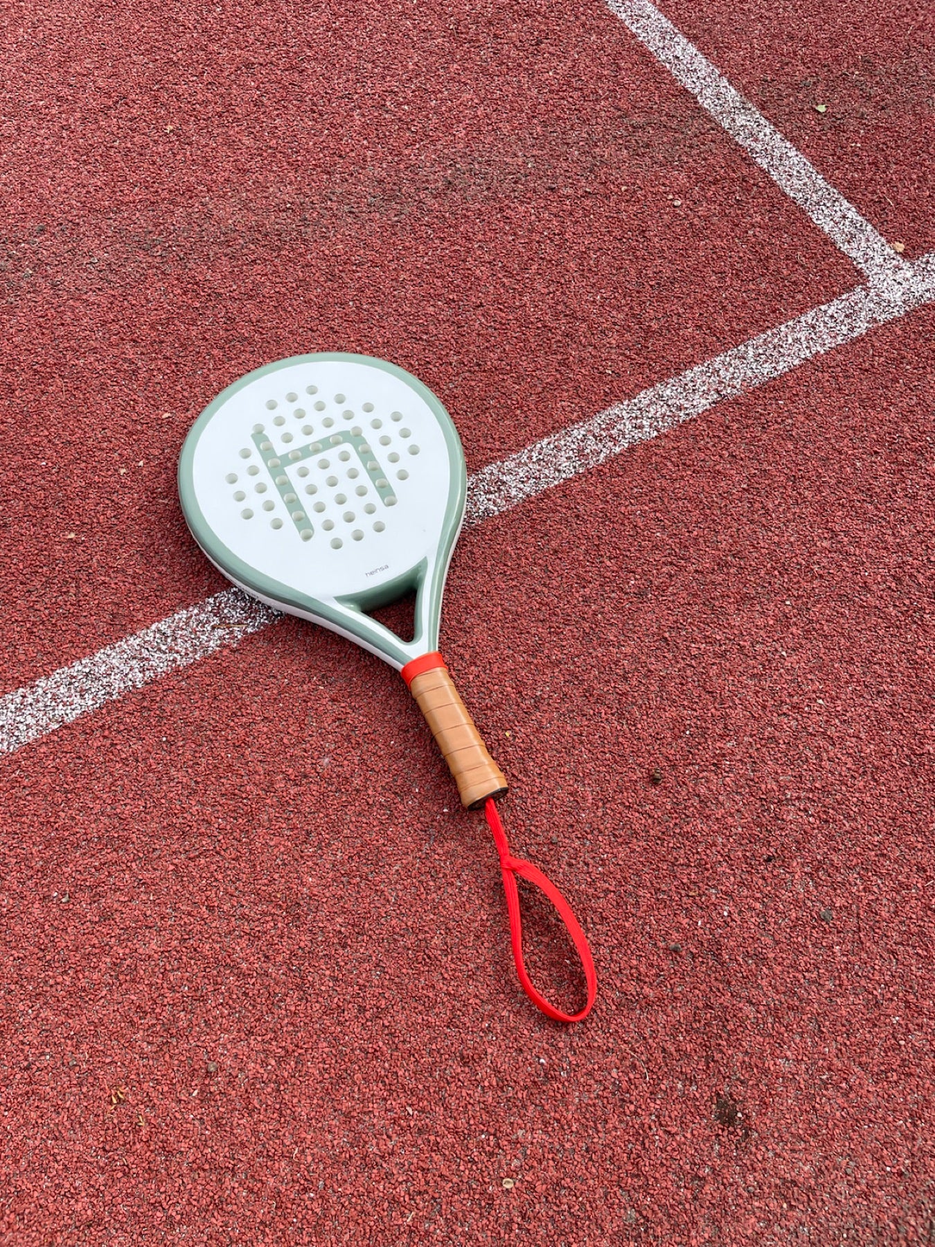 heinsa padel schläger auf einem roten court